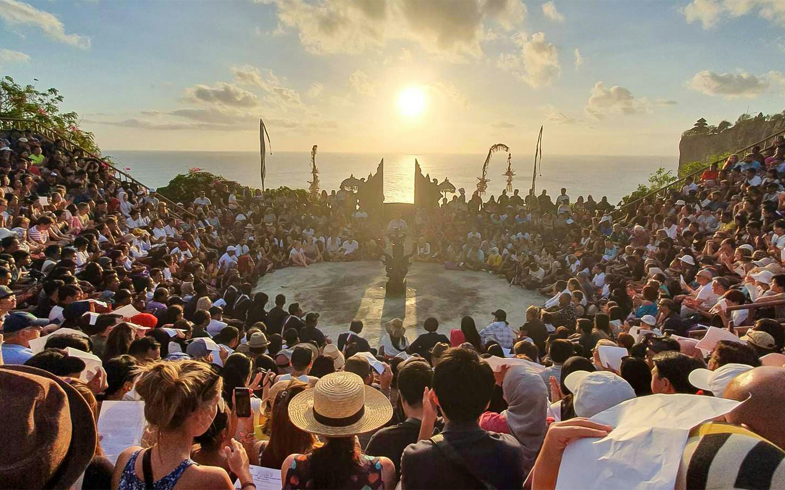 Audience watching Kecak dance at Uluwatu Temple, Bali, during sunset.