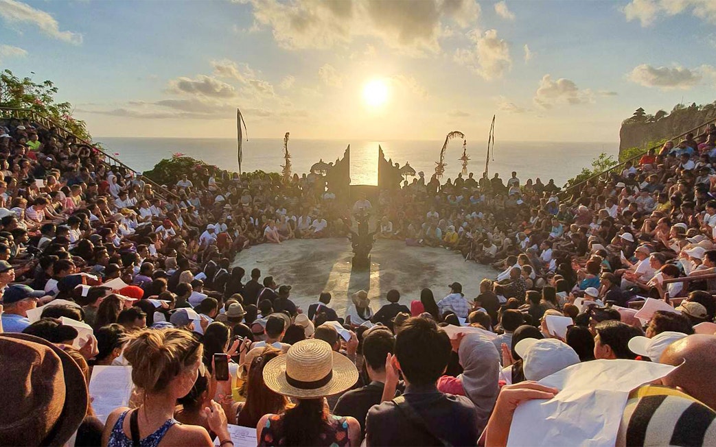Audience watching Kecak dance at Uluwatu Temple, Bali, during sunset.