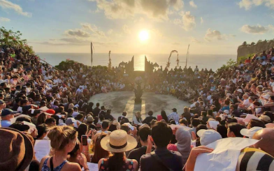 Audience watching Kecak dance at Uluwatu Temple, Bali, during sunset.