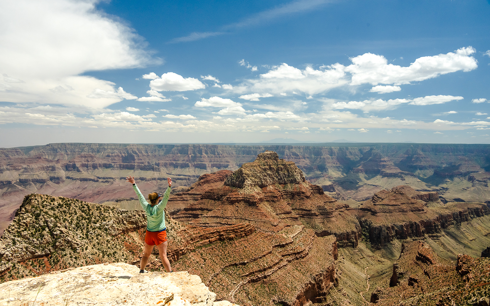 Woman standing at the end of Cape Final Trail, Grand Canyon, overlooking vast canyon landscape.