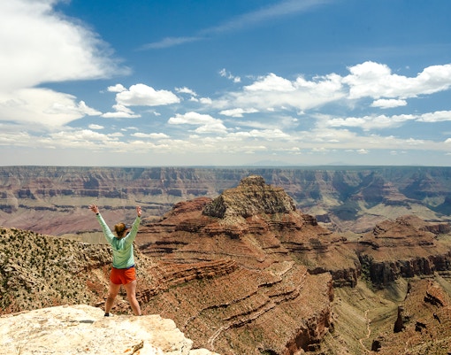 Woman standing at the end of Cape Final Trail, Grand Canyon, overlooking vast canyon landscape.