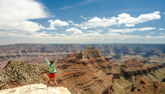 Woman standing at the end of Cape Final Trail, Grand Canyon, overlooking vast canyon landscape.