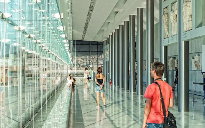 Visitors exploring the modern interior of the Athens Acropolis Museum.
