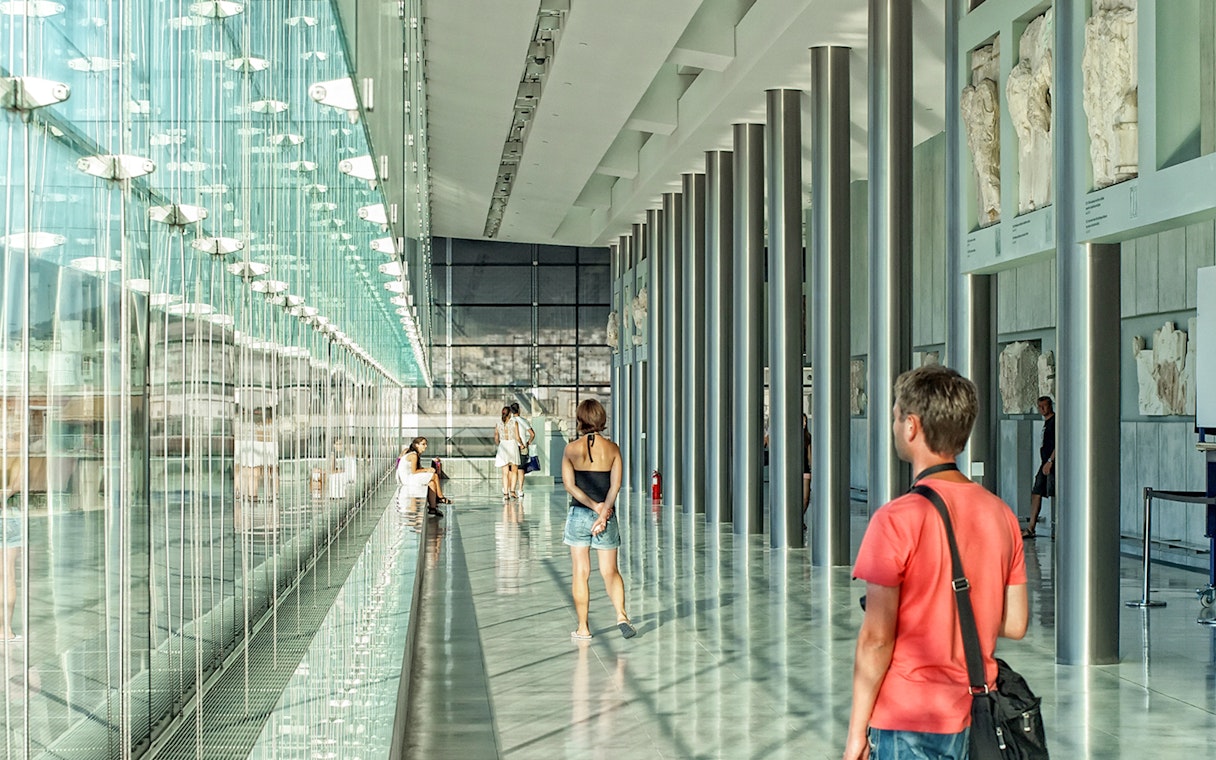 Visitors exploring the modern interior of the Athens Acropolis Museum.