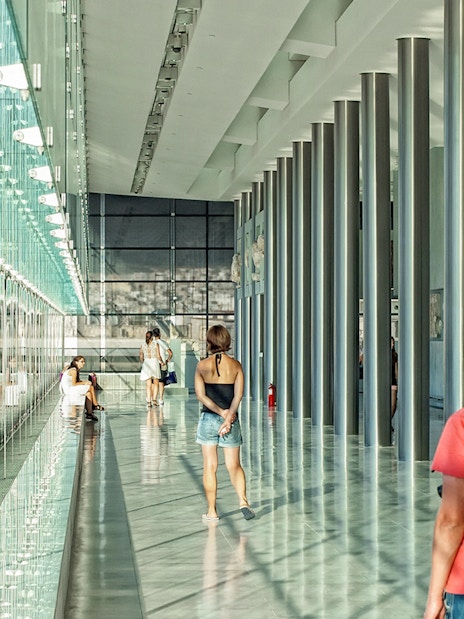 Visitors exploring the modern interior of the Athens Acropolis Museum.