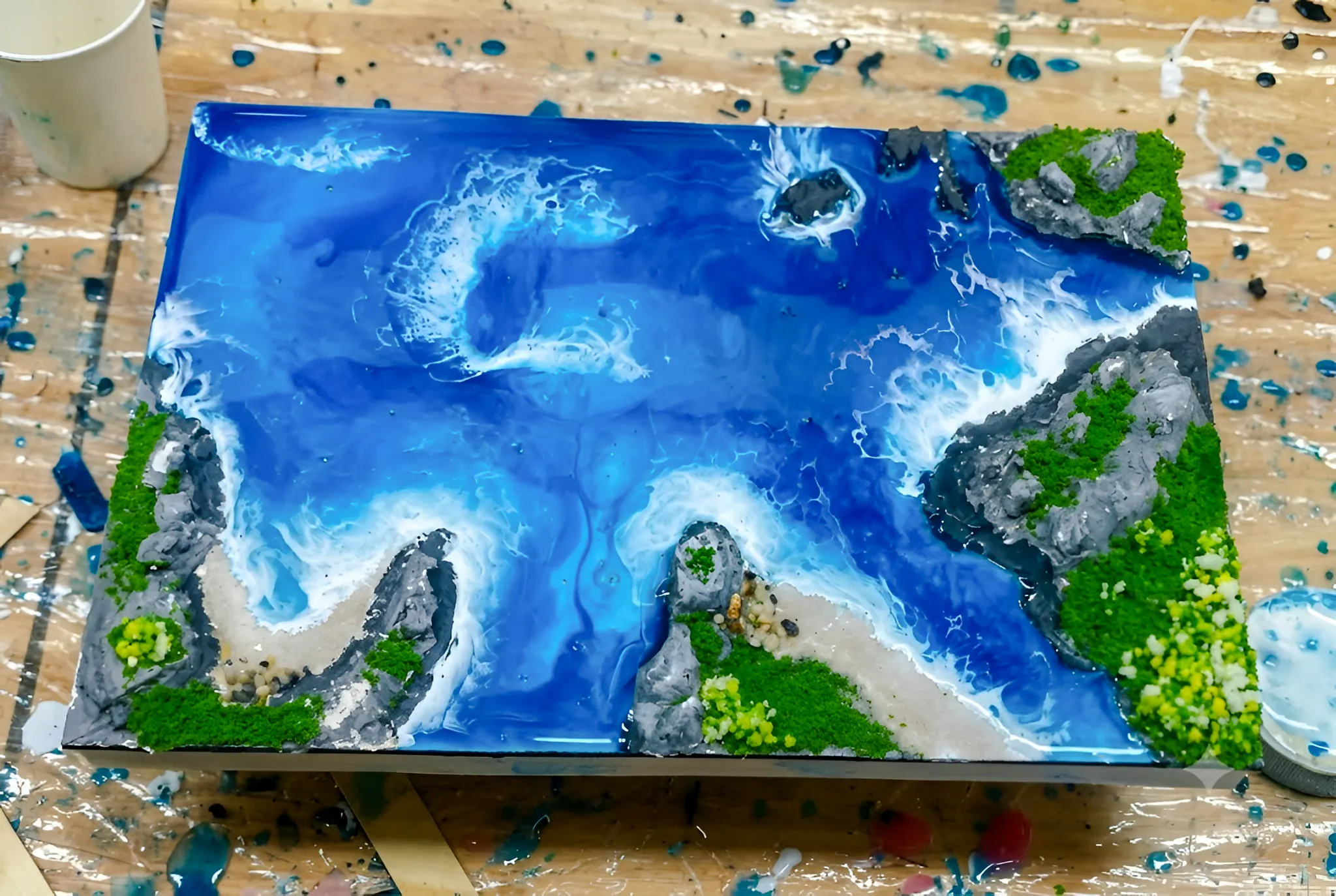 Miniature ocean scene artwork with waves and rocky shores, part of a creative experience in Hanoi.