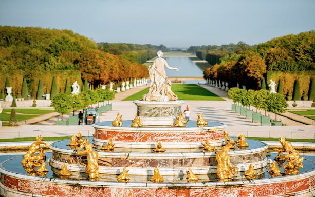 Fountain with golden statues in the gardens of the Palace of Versailles, Paris.