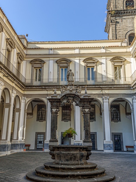 Cloister of San Lorenzo Maggiore in Naples with arched colonnades and central statue.