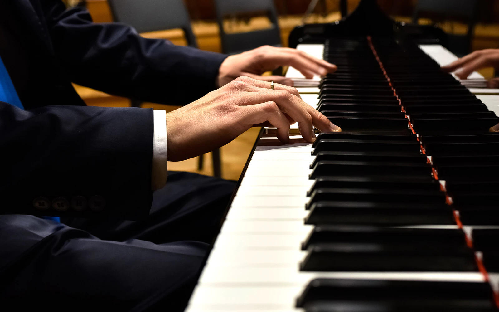 Pianist's hands playing a grand piano in a concert setting.