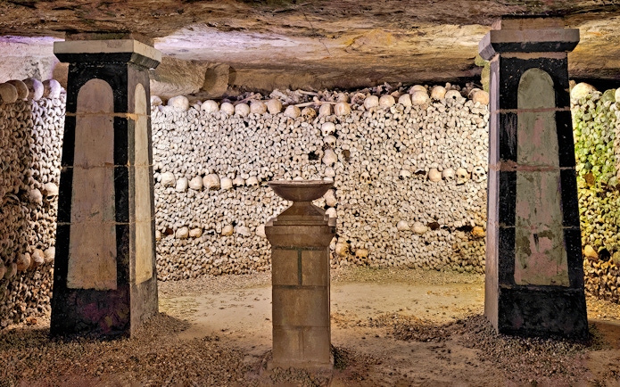 Sepulchral lamp in the Catacombs’ ossuary, Paris, surrounded by skulls and bones.