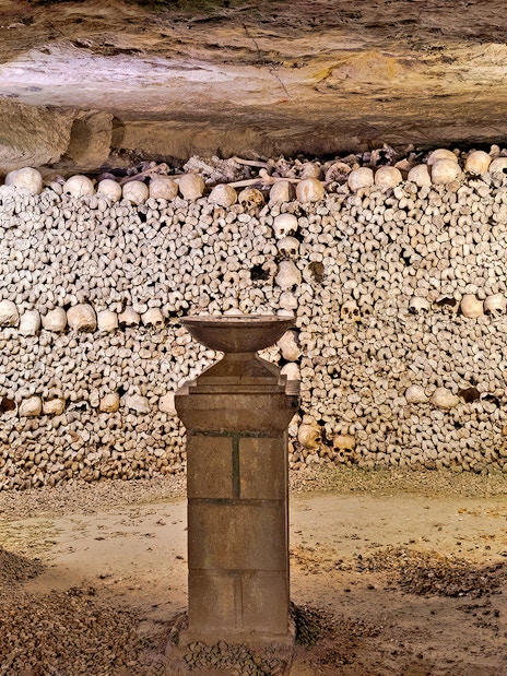 Sepulchral lamp in the Catacombs’ ossuary, Paris, surrounded by skulls and bones.