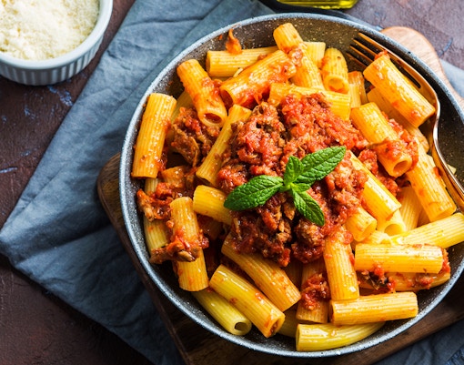 Homemade rigatoni pasta with tomato sauce and mint garnish, Italian cuisine.