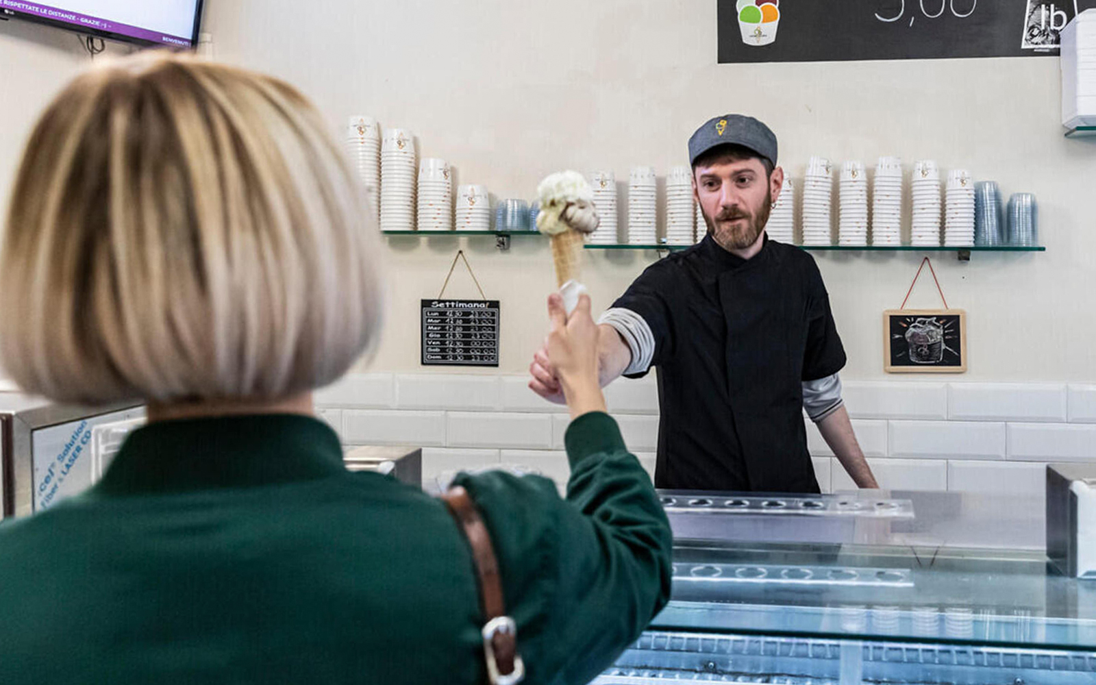 Gelato server handing cone to customer in Trastevere, Rome.