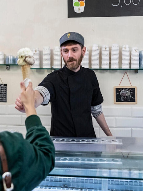 Gelato server handing cone to customer in Trastevere, Rome.