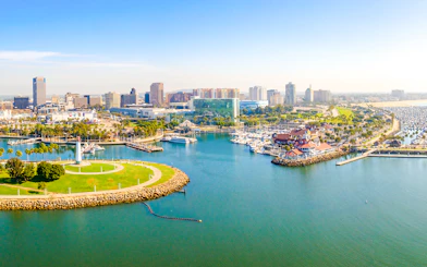 Aerial view of Long Beach coastline, harbor, skyline, and marina with boats and green park.