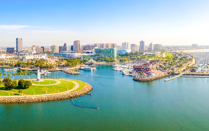Aerial view of Long Beach coastline, harbor, skyline, and marina with boats and green park.