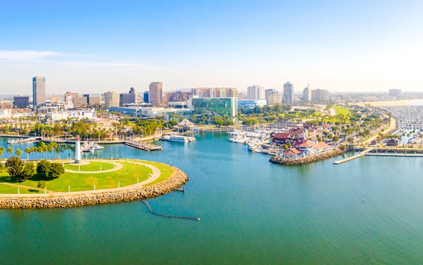 Aerial view of Long Beach coastline, harbor, skyline, and marina with boats and green park.