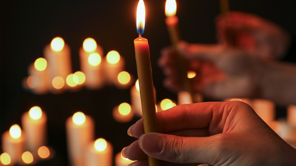 Woman holding a lit candle in a dimly lit room, closeup.