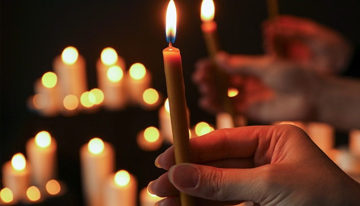 Woman holding a lit candle in a dimly lit room, closeup.