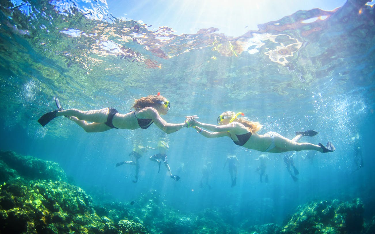 Snorkelers exploring coral reefs during luxury sail tour in Maui, Hawaii.