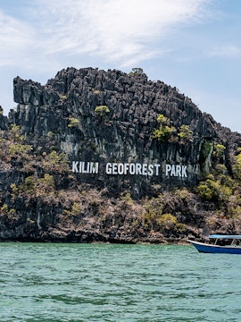 Kilim Geoforest Park limestone cliffs with boats on Langkawi Island.