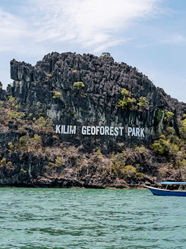 Kilim Geoforest Park limestone cliffs with boats on Langkawi Island.