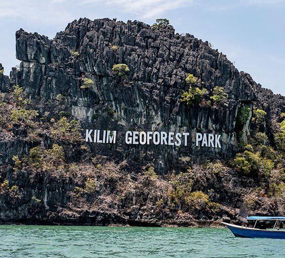 Kilim Geoforest Park limestone cliffs with boats on Langkawi Island.