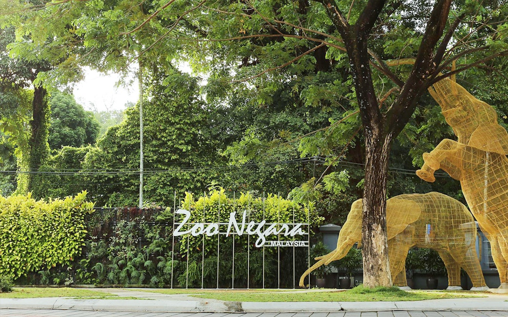 Zoo Negara entrance with animal sculptures and lush greenery, Malaysia.
