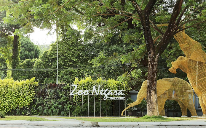 Zoo Negara entrance with animal sculptures and lush greenery, Malaysia.