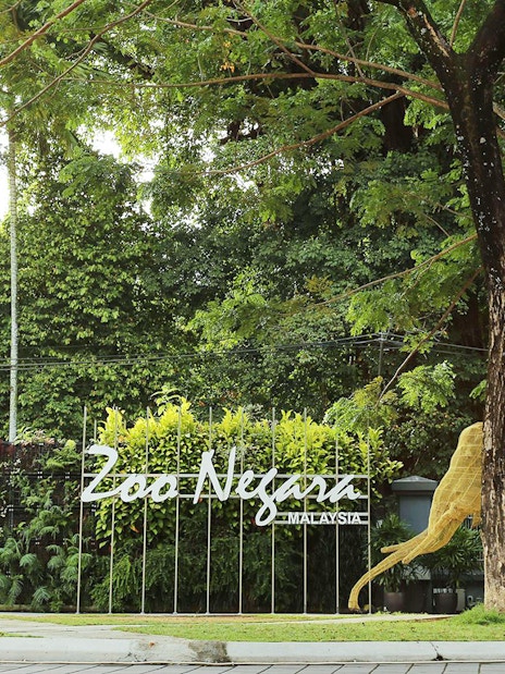 Zoo Negara entrance with animal sculptures and lush greenery, Malaysia.