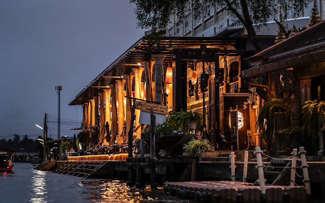 Amphawa Sri Cafe lit up at night along the canal in Amphawa, Thailand.