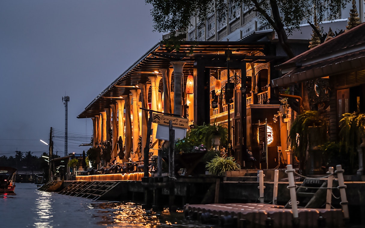 Amphawa Sri Cafe lit up at night along the canal in Amphawa, Thailand.