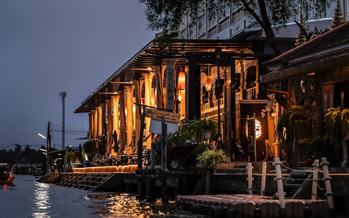 Amphawa Sri Cafe lit up at night along the canal in Amphawa, Thailand.