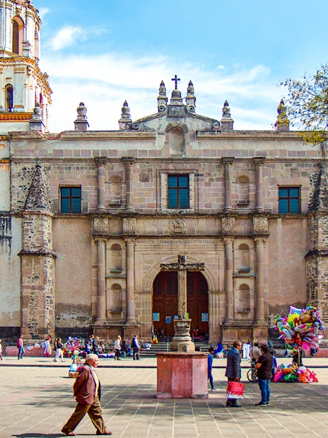 Parroquia San Juan Bautista facade with people in plaza, Mexico.