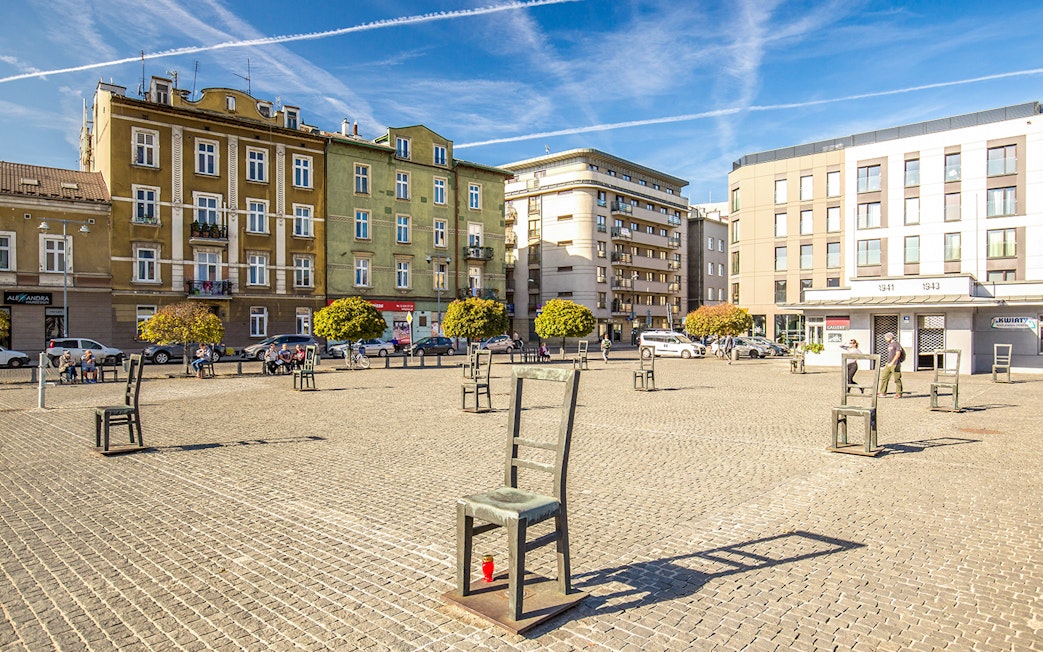 Krakow Jewish Ghetto square with empty chair sculptures and historical buildings.