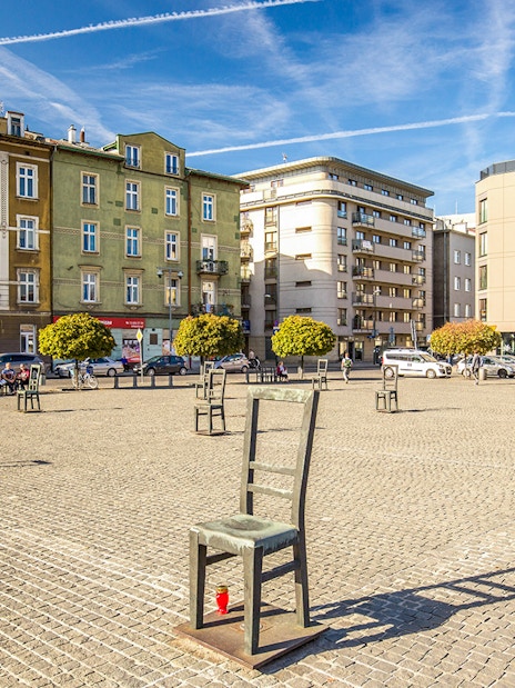 Krakow Jewish Ghetto square with empty chair sculptures and historical buildings.