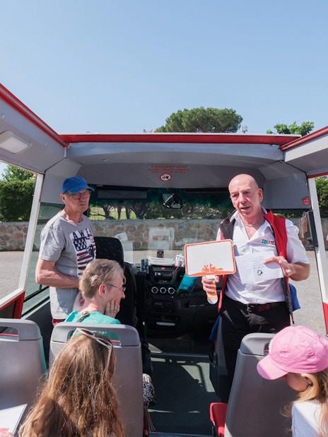 Tour guide speaking to visitors on a bus at Catacombs of Domitilla, Rome.