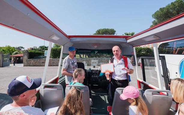 Tour guide speaking to visitors on a bus at Catacombs of Domitilla, Rome.