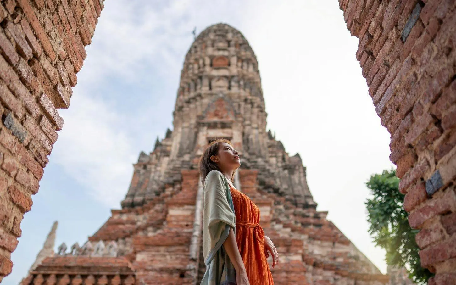 Woman standing in front of ancient temple ruins at Ayutthaya, Thailand.