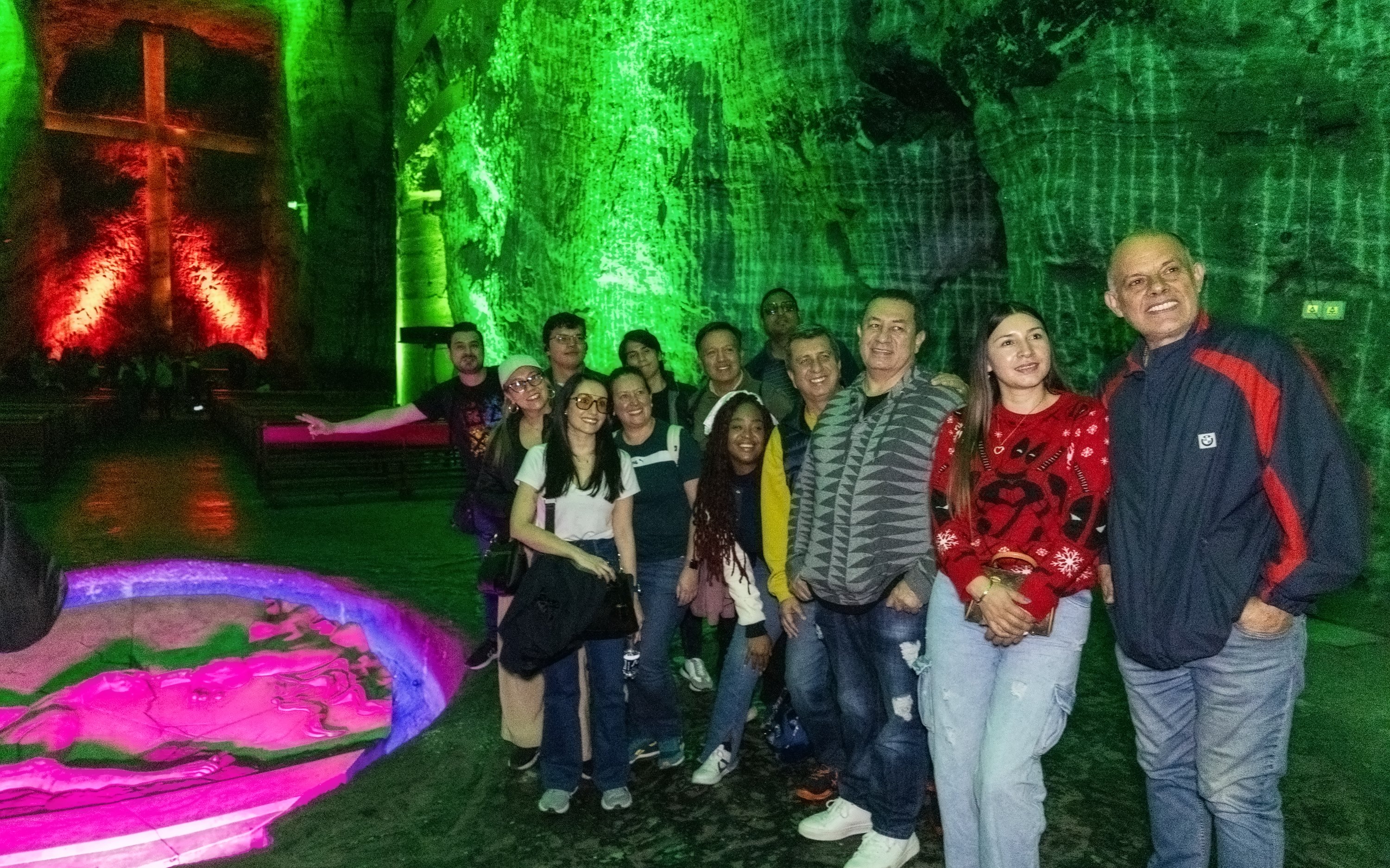 Tourists inside Zipaquira Salt Cathedral with illuminated cross in background.