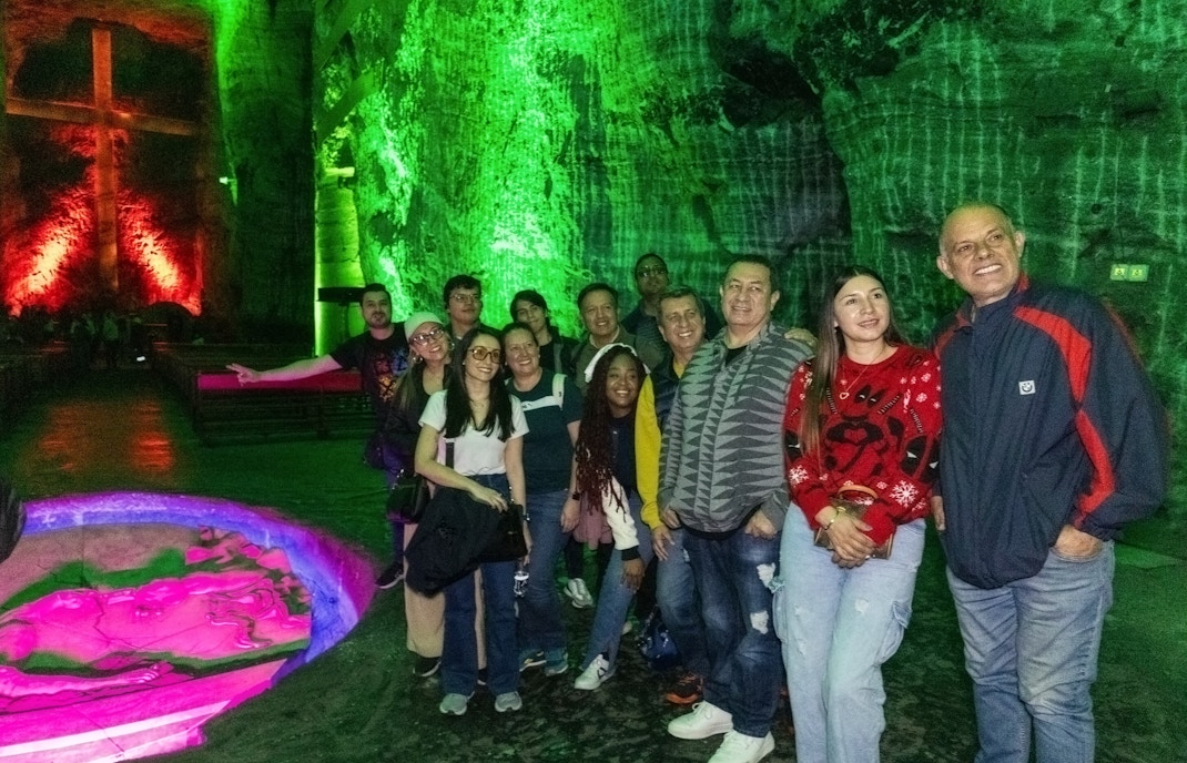 Tourists inside Zipaquira Salt Cathedral with illuminated cross in background.