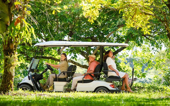 Tourists riding a golf cart through lush greenery at Australia Zoo.
