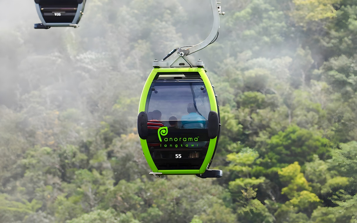 Langkawi Cable Car gondola ascending over lush green forest.
