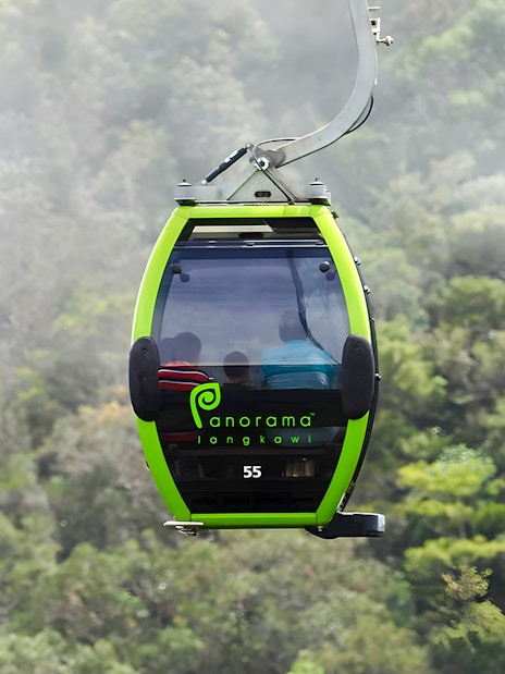 Langkawi Cable Car gondola ascending over lush green forest.