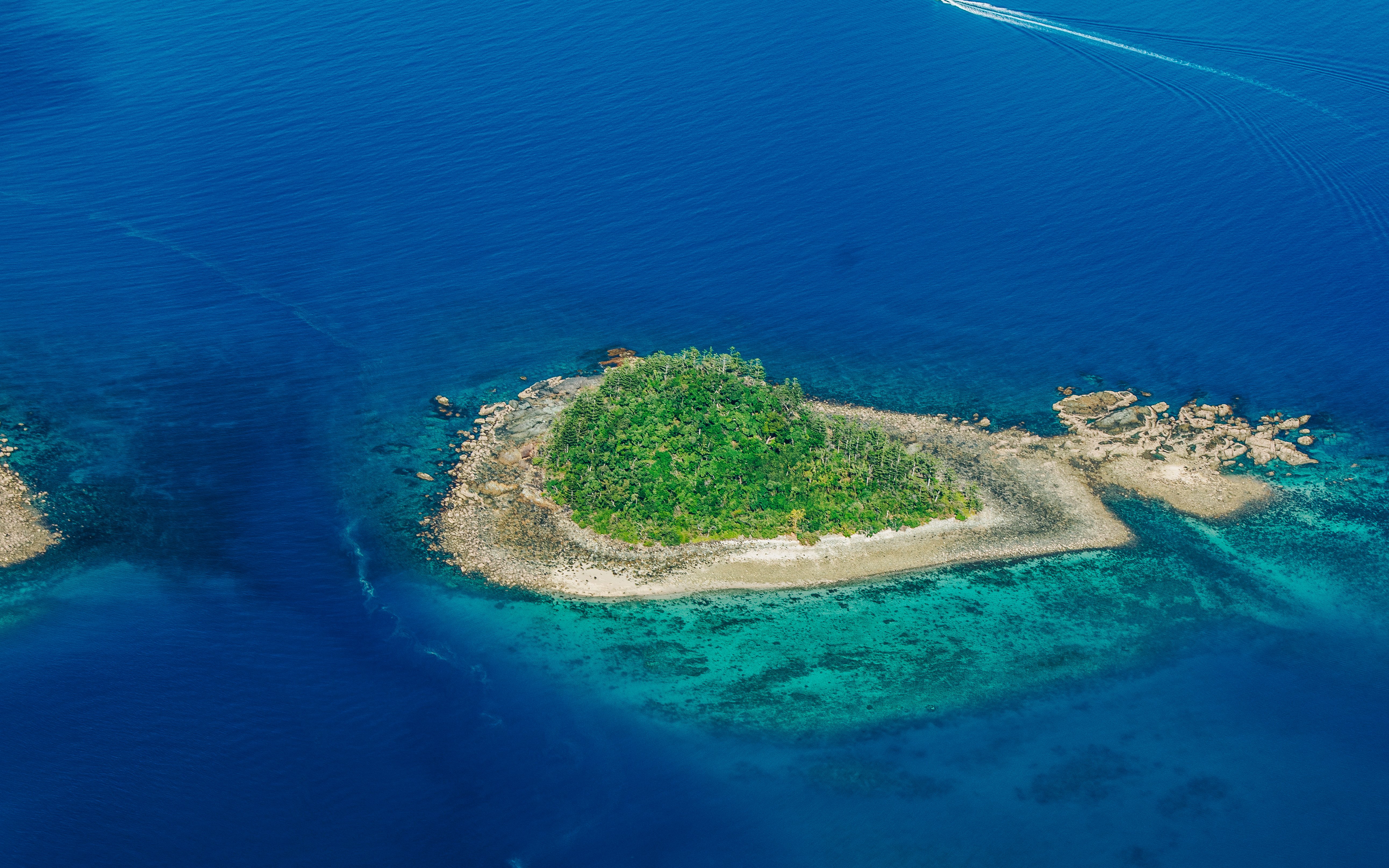 Aerial view of a small island surrounded by blue ocean near Airlie Beach.