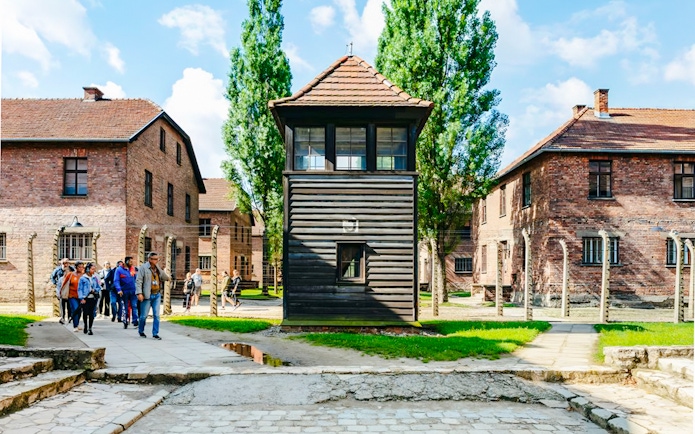 Group touring Auschwitz I with watchtower in view, part of a small guided tour.