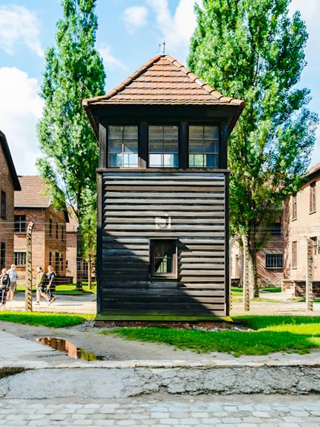 Group touring Auschwitz I with watchtower in view, part of a small guided tour.
