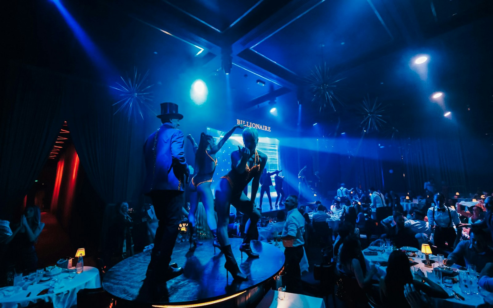 Dancers performing on stage at Billionaire Dubai with guests dining.