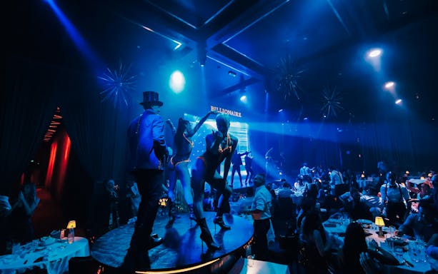 Dancers performing on stage at Billionaire Dubai with guests dining.