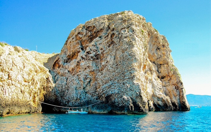 Bisevo Island Blue Cave entrance with boat on clear water.